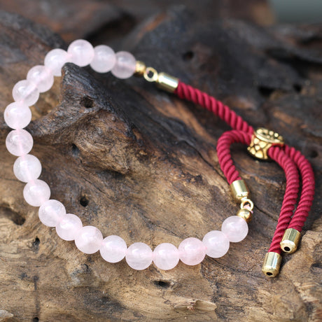 A rose quartz beaded bracelet on a red strong and golden fittings, on a wooden surface 