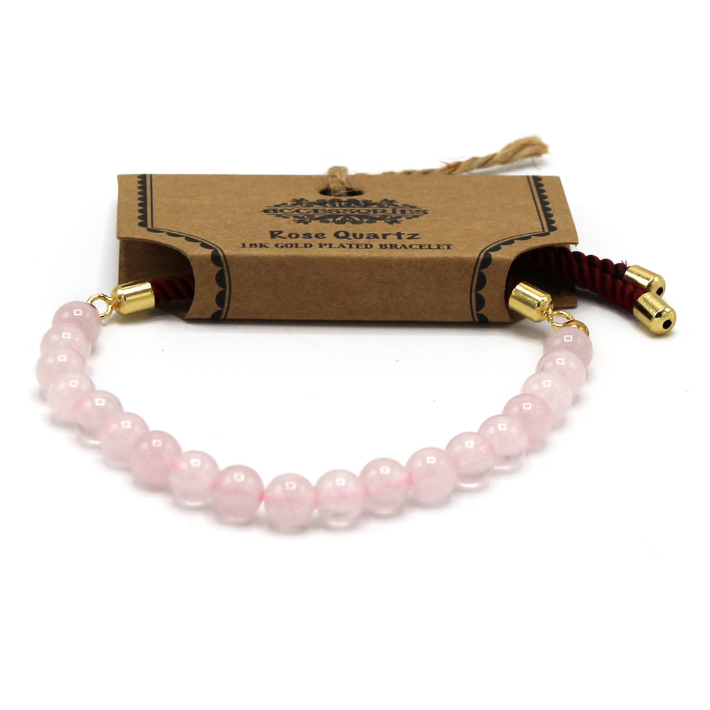 A rose quartz beaded bracelet on a red strong and golden fittings, on a white surface 