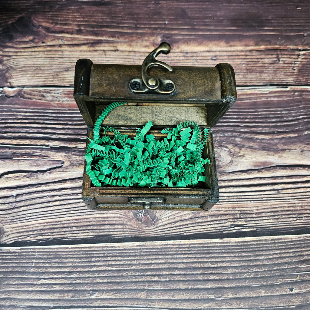 A small brown "treasure chest" open with green paper inside. 