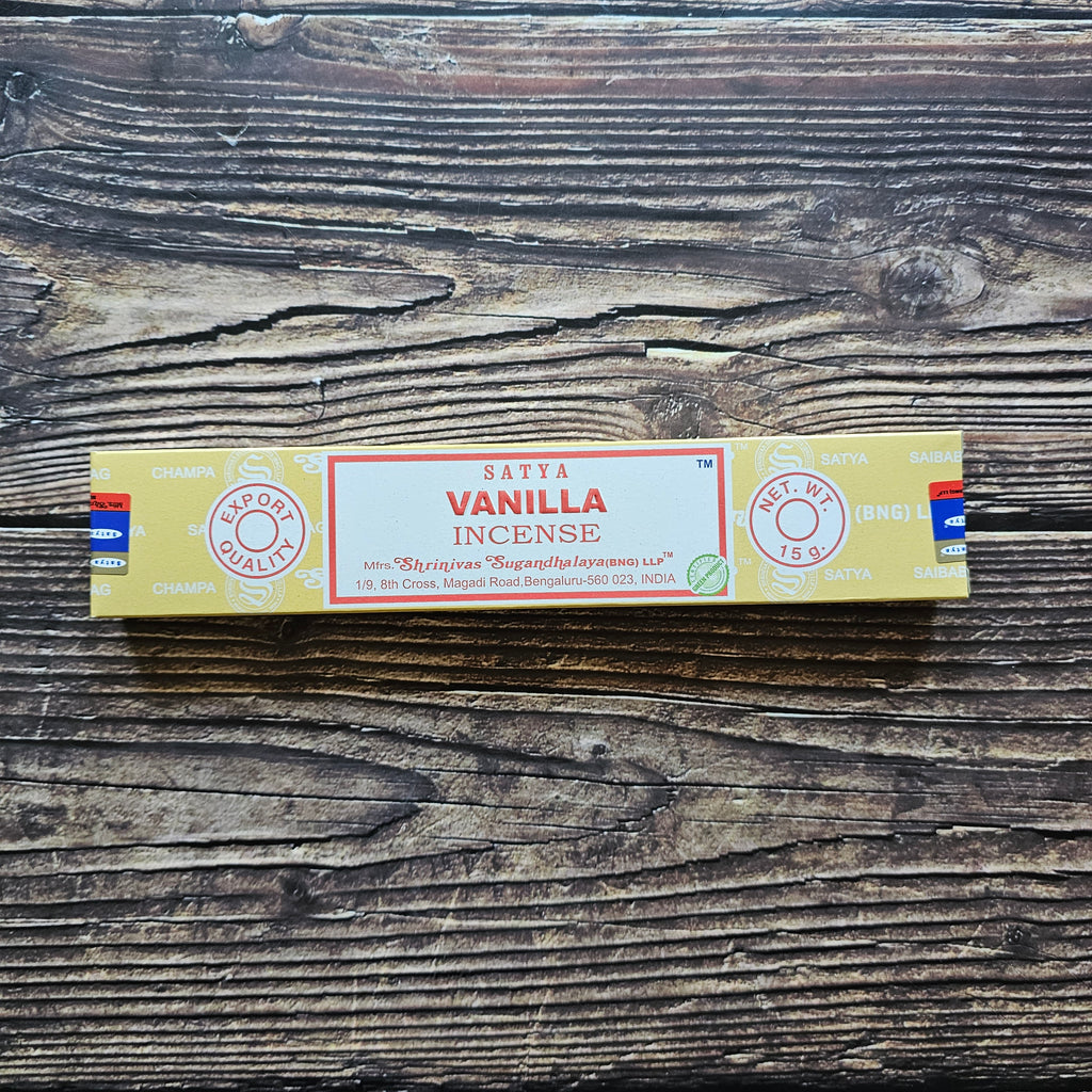 A pack of Satya incense sticks with the label 'VANILLA' displayed on the packaging. Laid on a wooden background. 