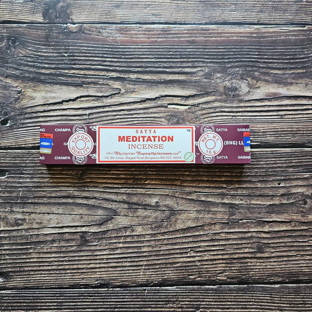 A pack of Satya incense sticks with the label 'MEDITATION' displayed on the packaging. Laid on a wooden background. 