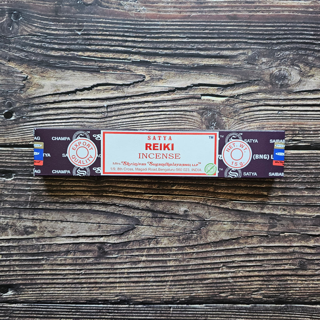 A pack of Satya incense sticks with the label 'REIKI' displayed on the packaging. Laid on a wooden background. 