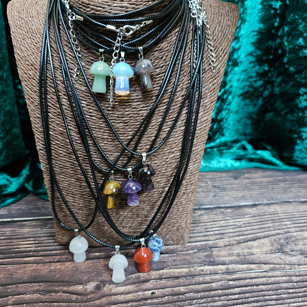 A collection of mushroom-shaped crystal pendants in various colours attached to black cords, displayed on a mannequin