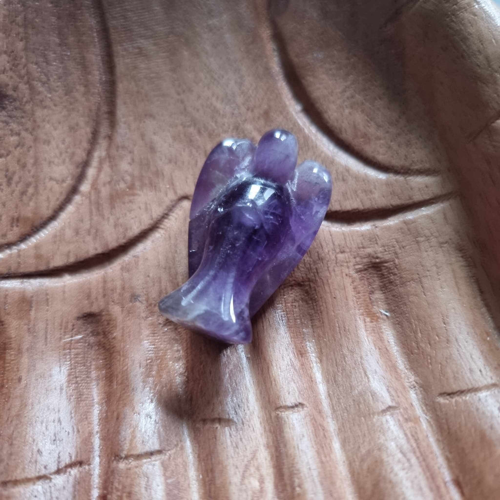 A purple crystal angel on a wooden backdrop 