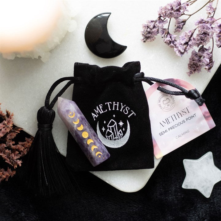 An Amethyst crystal point with gold-tone moon phase engraving, accompanied by a matching drawstring bag.