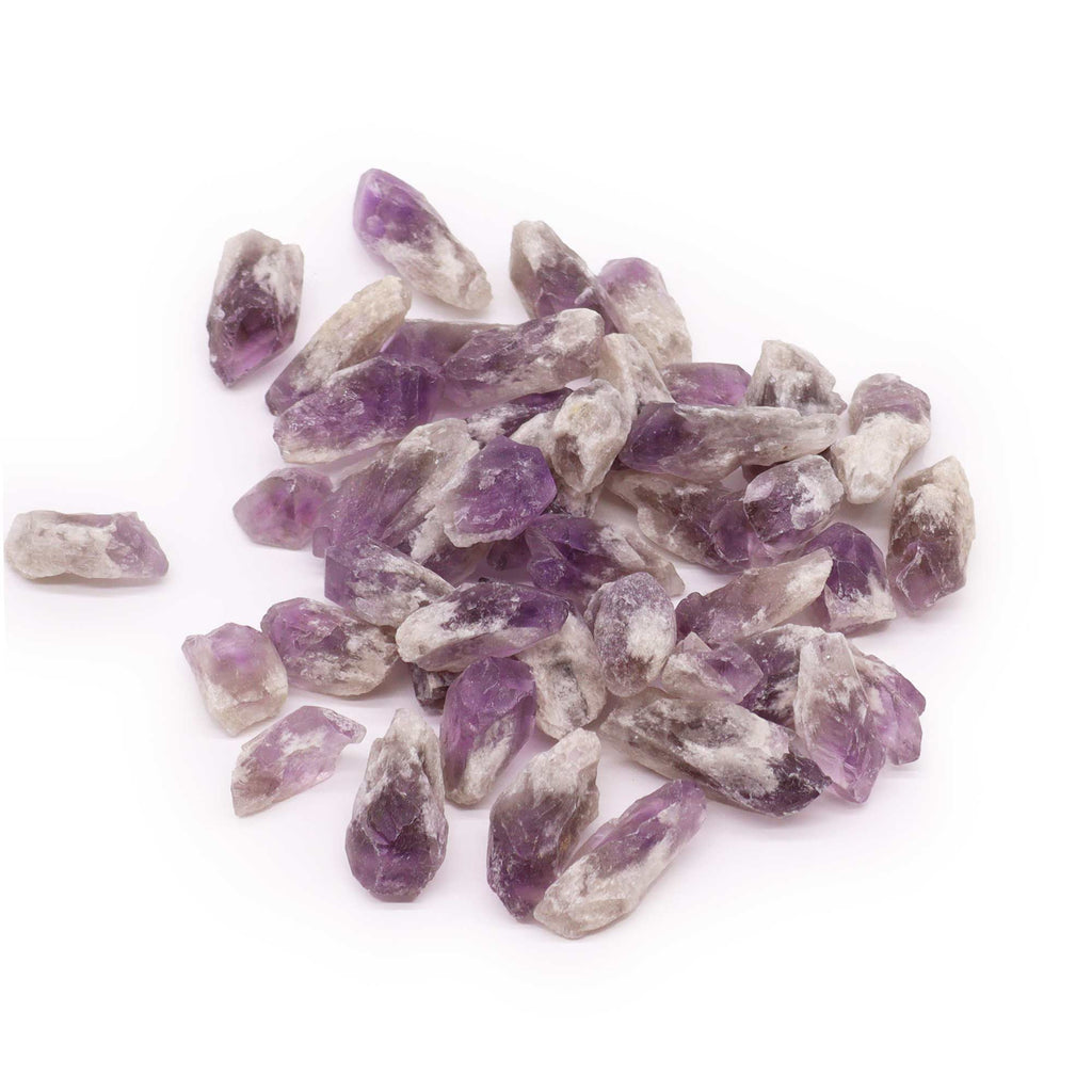 A collection of rough Amethyst pointed crystals against a white surface 