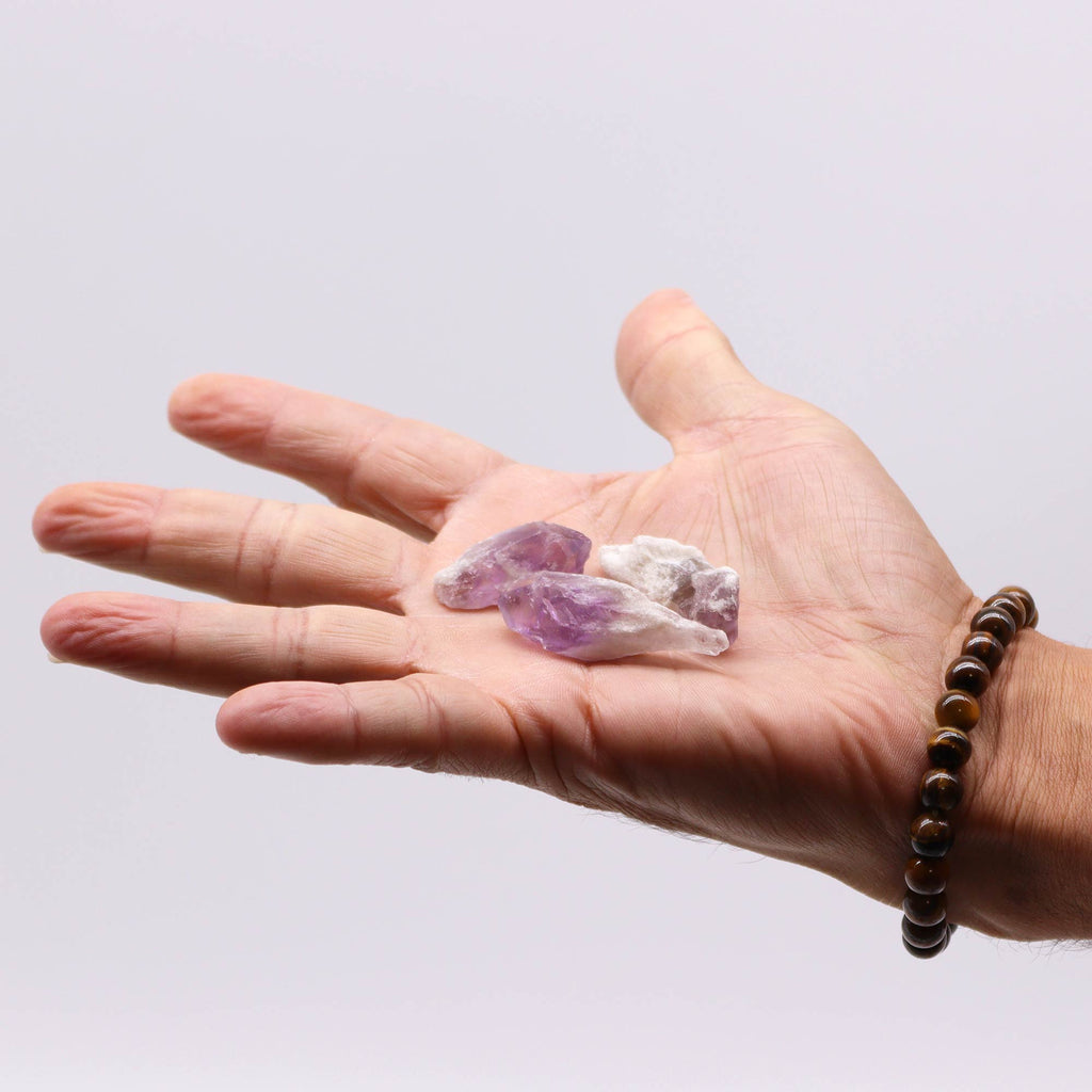 A collection of rough Amethyst pointed crystals held in a hand