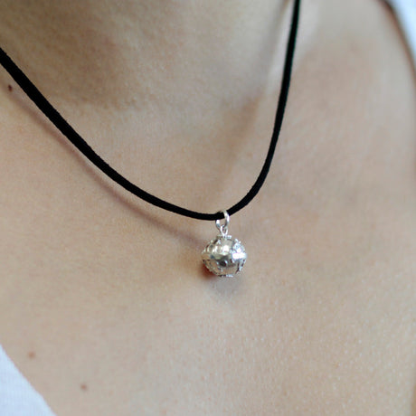 A silver angel bell necklace with a black cord, made of 92.5 silver in Bali.