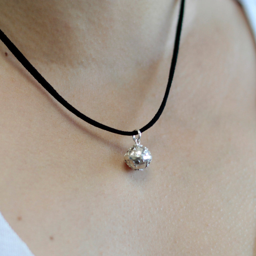 A silver angel bell necklace with a black cord, made of 92.5 silver in Bali.