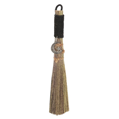 A small traditional broom with a jute string binding and a metal charm, commonly used for spiritual purposes.