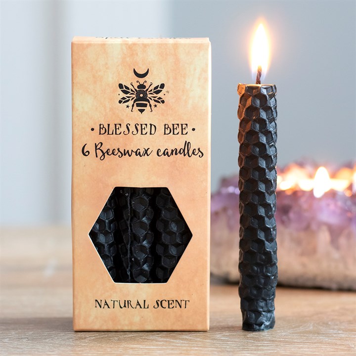 A box of black beeswax candles displayed next to a freestanding lit black candle
