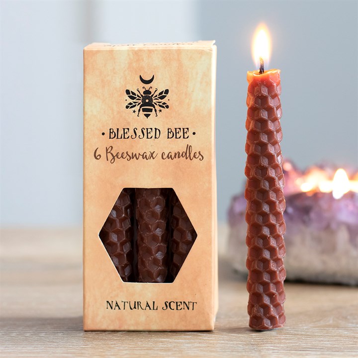 A box of brown beeswax candles displayed next to a freestanding lit brown candle