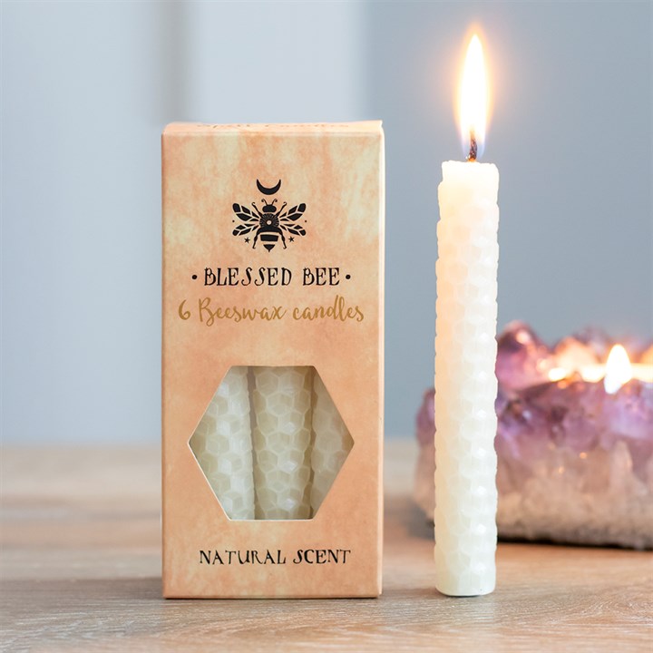 A box of white beeswax candles displayed next to a freestanding lit white candle