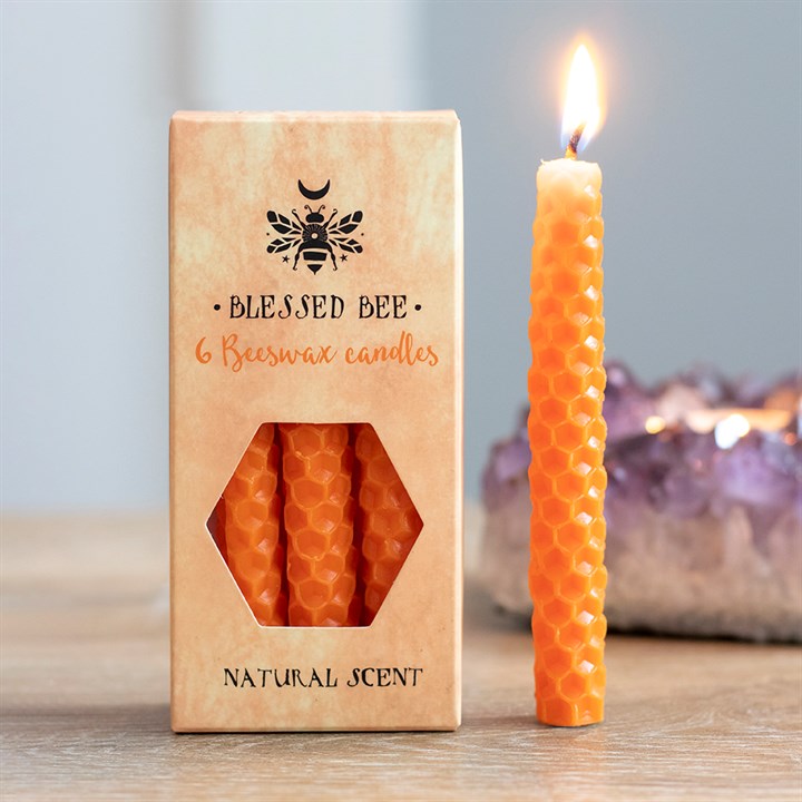 A box of orange beeswax candles displayed next to a freestanding lit orange candle
