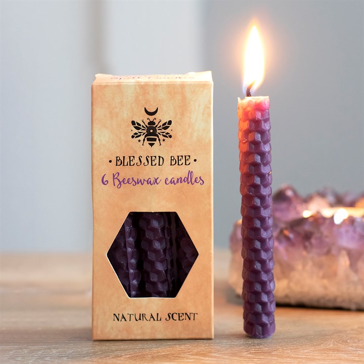 A box of purple beeswax candles displayed next to a freestanding lit purple candle