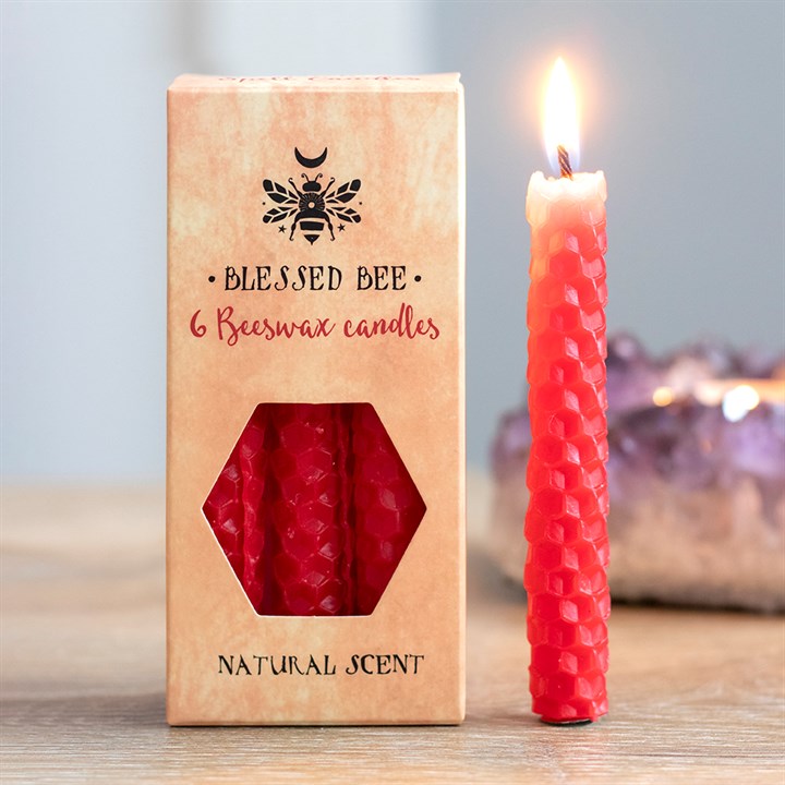 A box of red beeswax candles displayed next to a freestanding lit red candle
