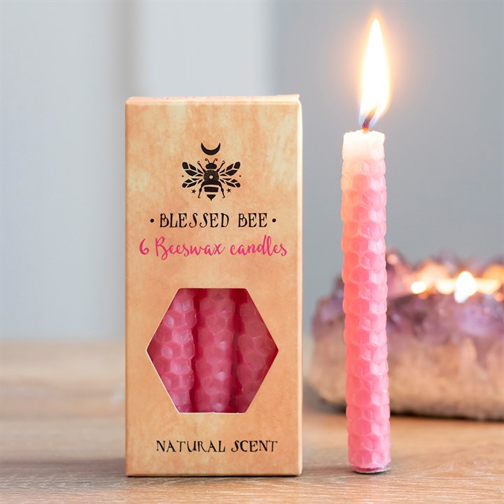 A box of pink beeswax candles displayed next to a freestanding lit pink candle