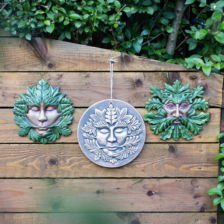 A "Green Goddess" green man themed plaque hung up on a shed outside next to other similar plaques 