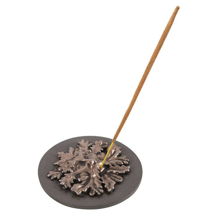 A bronze-effect green man incense holder made of resin, with an incense stick, displayed against a white background