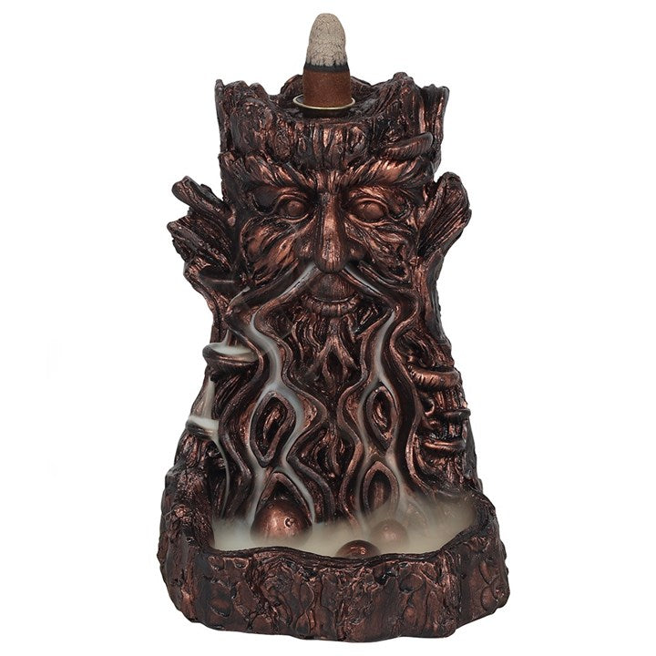 A bronze-looking back flow incense holder in a green man design with a lit incense cone showing the smoke drift down its beard