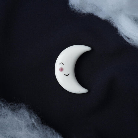 Crescent moon-shaped character with a smiling face on a dark background