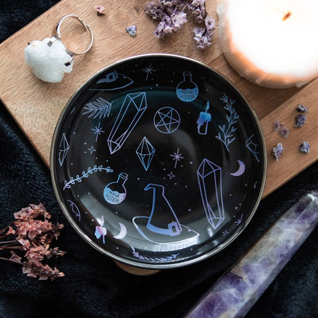 A round trinket bowl with witch hat and crystals/herbs design on a decorative background