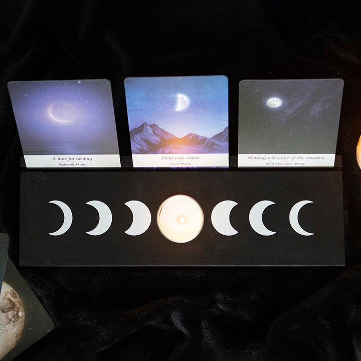 A large black moon phases design tarot and oracle card stand with three cards, displayed on a dark background.