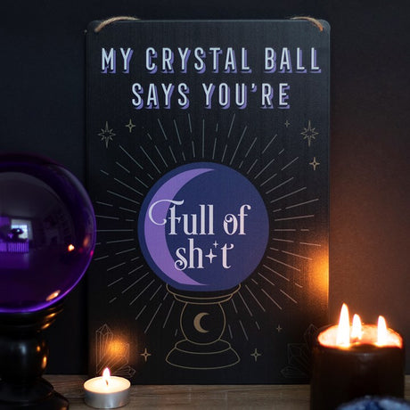 A black tin sign states "My Crystal Ball Says you're Full of Sh*t" and has a purple crystal ball with golden decor