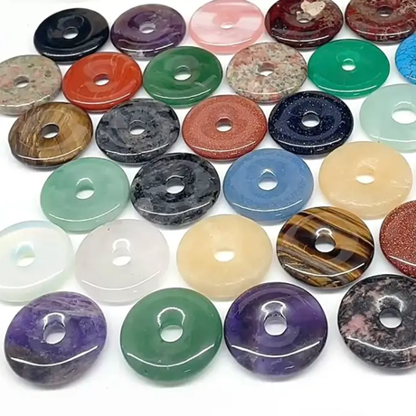 Assorted colourful crystal donut pendants on a white background