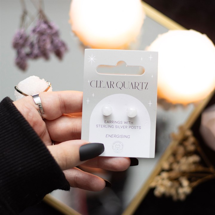 A hand holding Clear quartz crystal stud earrings displayed on a card. 