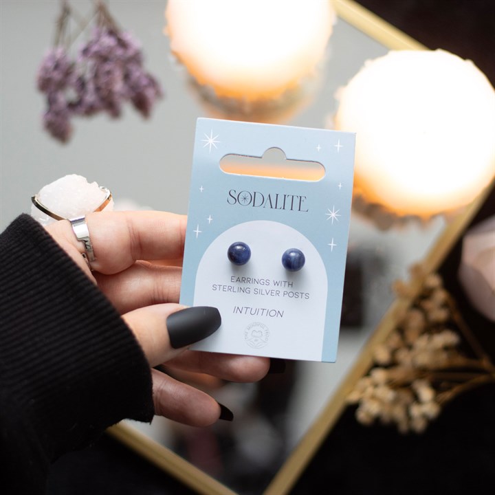 A hand holding Sodalite crystal stud earrings displayed on a card. 