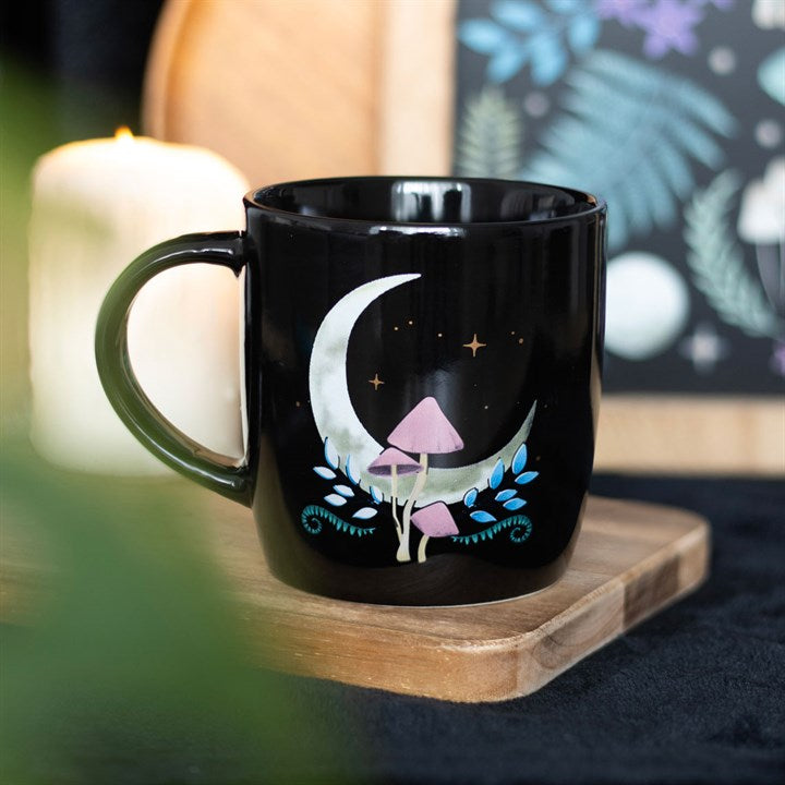 A dark forest mushroom and crescent moon mug displayed on a wooden tray. 