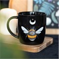 A dark forest, bee mug with, displayed on a wooden tray.