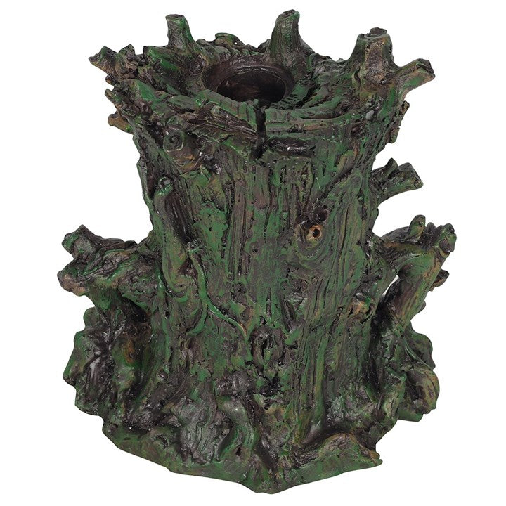 A dark-coloured back flow incense burner designed to resemble a stylised green man face with leaf-like patterns, featuring a lighted crystal cave for smoke to flow through, set against a white backdrop.