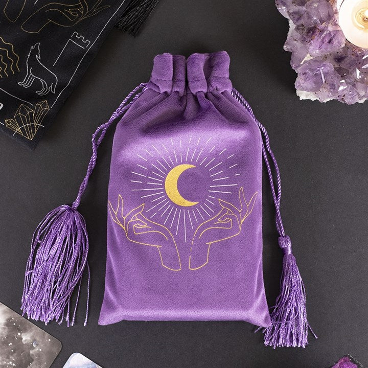 A purple silky looking bag with tassels; it has hands and the moon on it