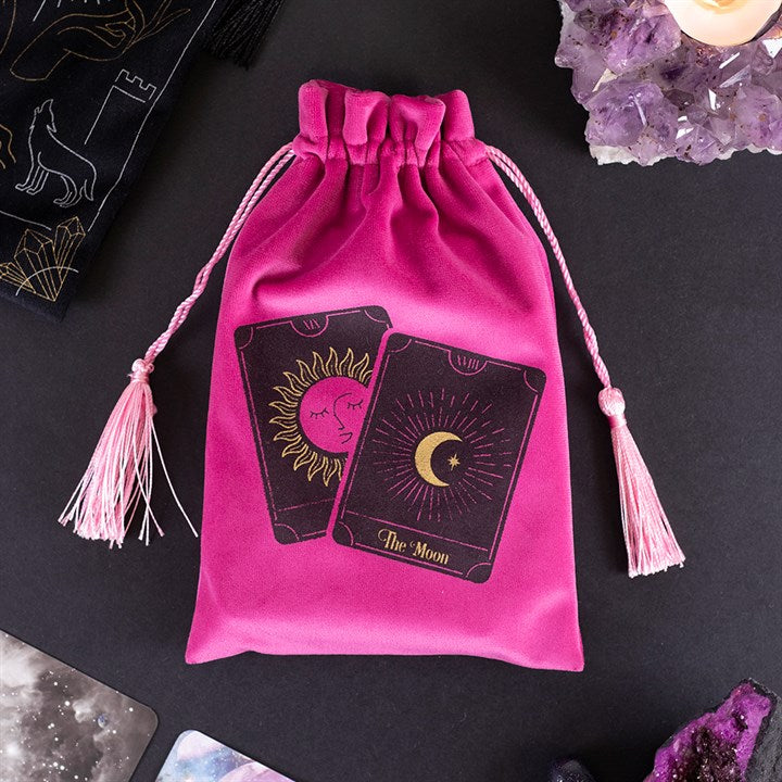 A pink silky looking bag with tassels; it has two tarot cards on it, one is the sun, the other is the moon