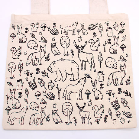 A cream bag which has black lined drawings of various animals such as bears, wolves, hedgehogs, owls, squirrels and some plant life such as acorns, trees and herbs