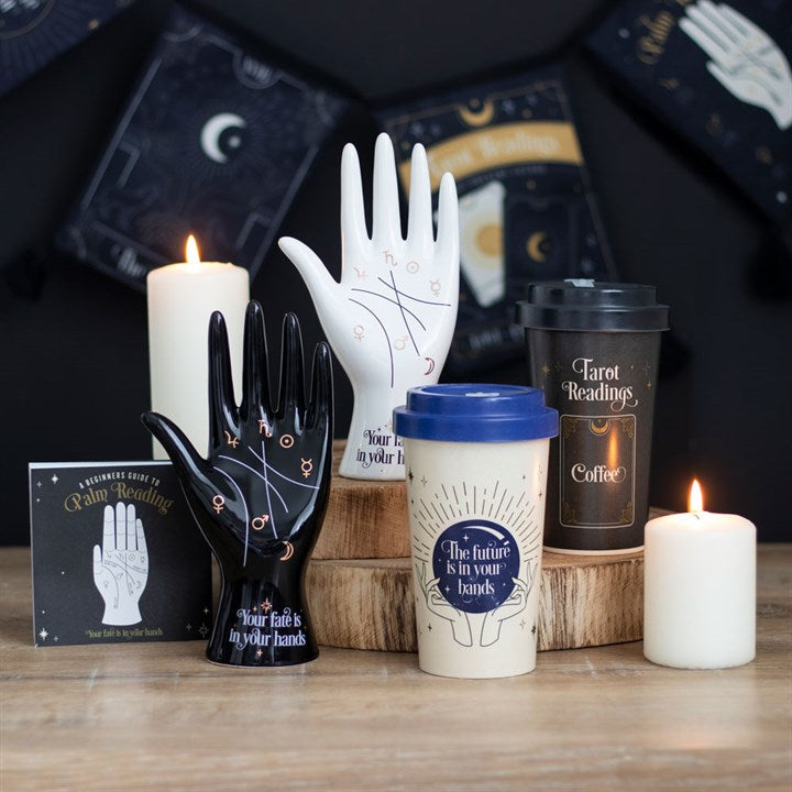 A selection of tarot and palm reading accessories such as standing ceramic hands with palmistry decor and eco travel mugs.