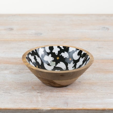 Wooden bowl with a black interior featuring white ghost patterns on a wooden surface