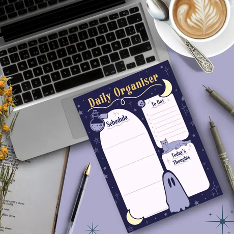 Daily planner on a desk with a laptop, coffee, and stationery items.
