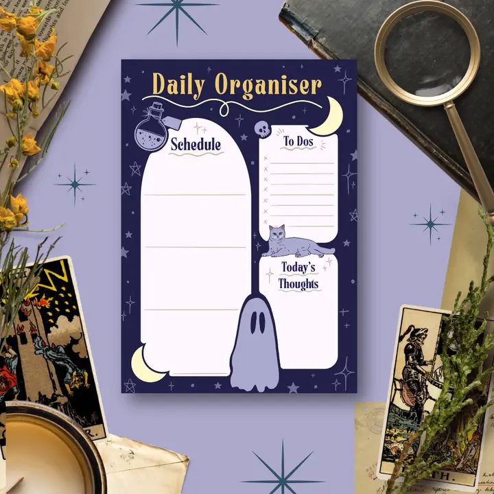 Daily organiser with ghost design on a purple background surrounded by tarot cards and decorative items.