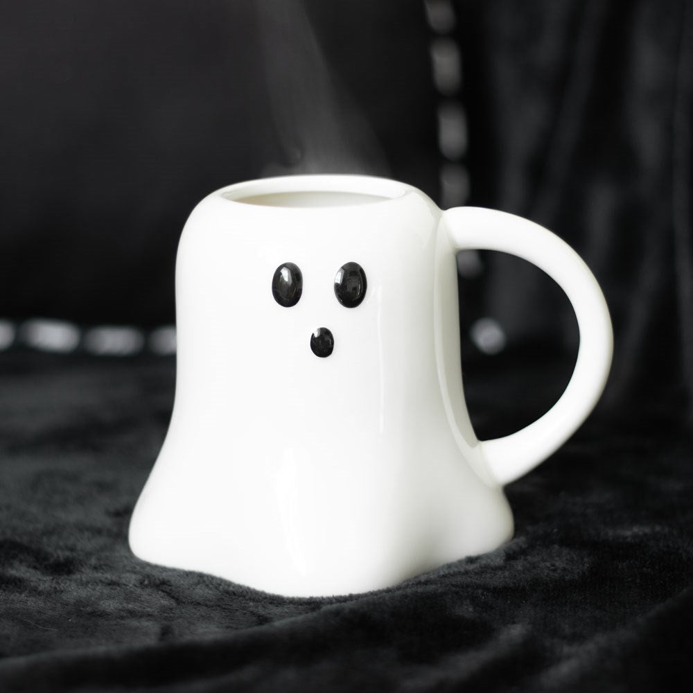A white ceramic ghost-shaped mug, displayed on a dark surface