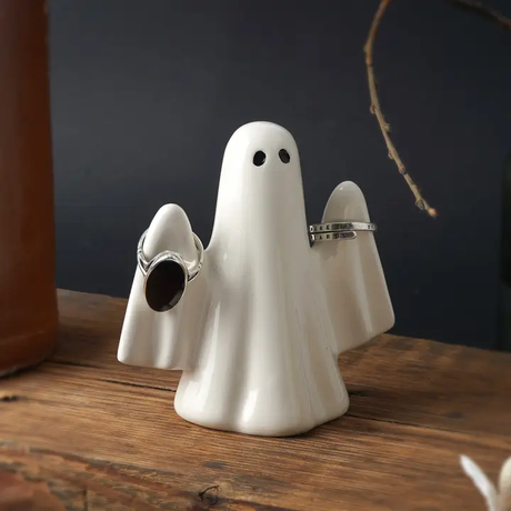 White ghost-shaped ring holder with rings on a wooden surface
