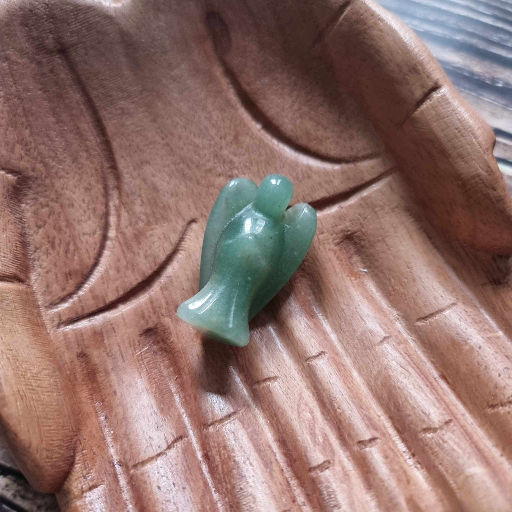 A green crystal angel on a wooden backdrop 