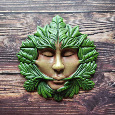 A "Green Goddess" green man themed plaque on a wooden background