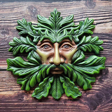 A Green Man themed plaque laid on a wooden surface 