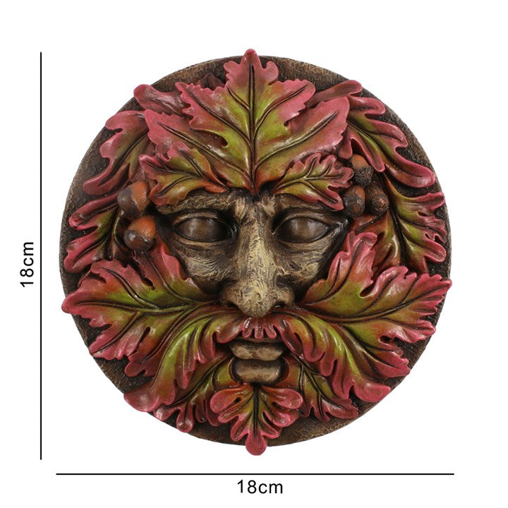 A round plaque in a green man design against a whtie background