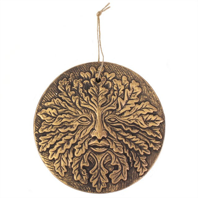 A round terracotta plaque with a bronze effect finish, featuring the Green Man symbol with leaf patterns for eyes and branches for a nose and mouth, mounted on a twine loop against a white background.