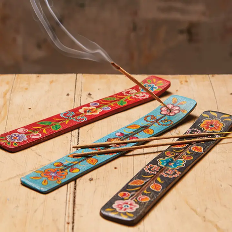 Colourful incense holders with floral patterns on a wooden surface.