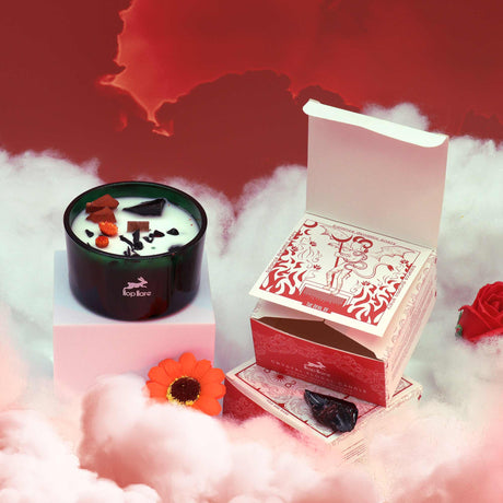 A green glass candle with red and orange dried flowers and red and black crystals. There is a red sky background and a cloud detailing. There is also a matching "devil" box. 